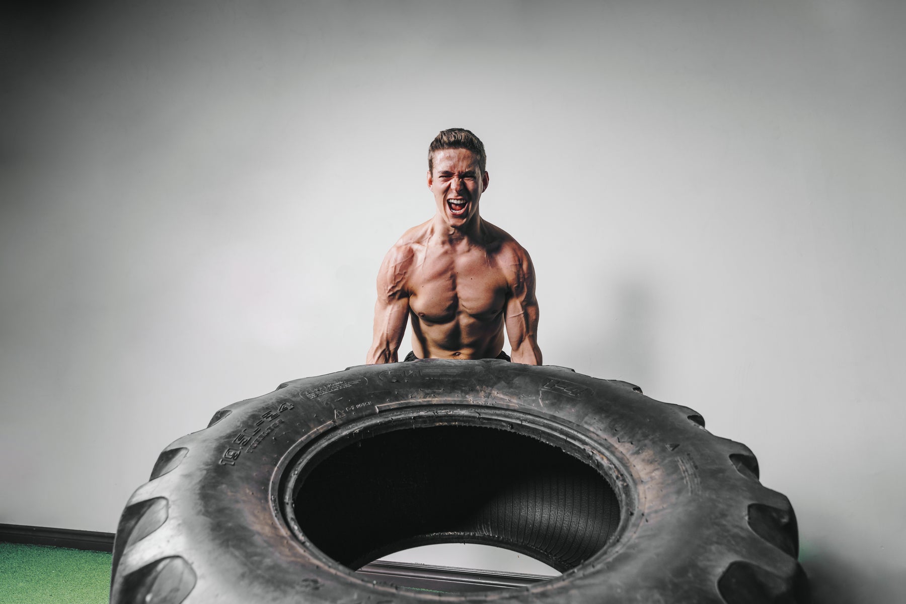 An athlete performing a tire-flip exercise, post-workout skin under real training stress.